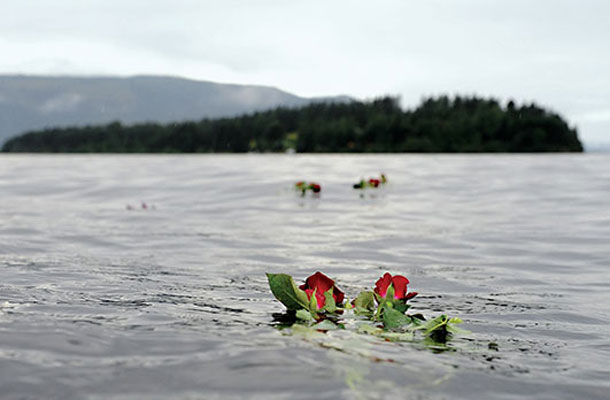 Rože na gladini jezera v spomin žrtvam pokola. Zadaj otok Utoya, kjer se je zgodil nepojmljiv zločin.