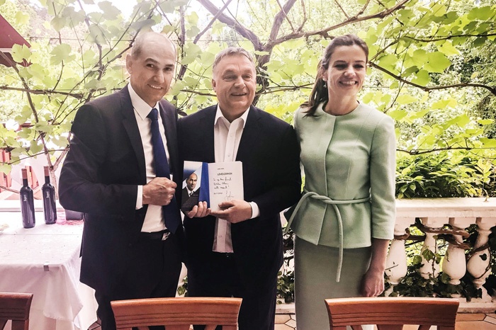 Fotografi ja, ki jo je Janez Janša objavil na svojem Twitter profi lu. Na njej je Janša s svojo ženo Urško Bačovnik in premier Madžarske Victor Orban z Janševo knjigo Okopi, ki je izšla v madžarščini. Janša je v knjigo napisal posvetilo v angleščini: »Mojemu dragemu prijatelju Viktorju Orbanu, s spoštovanjem.«