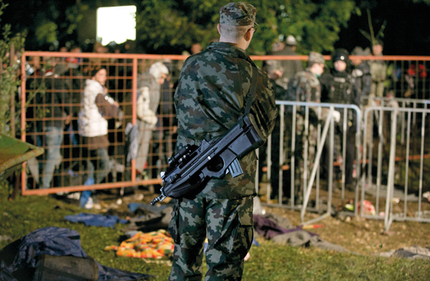 Torek zvečer, nastanitveni center v nekdanji šivalnici tovarne Beti v Dobovi. Ljudi vodijo k avtobusom. Pomaga vojaška policija. Na sliki vojak z avtomatsko puško F2000, kupljeno po standardih Nata. Hitrost streljanja: 850 nabojev na minuto. 