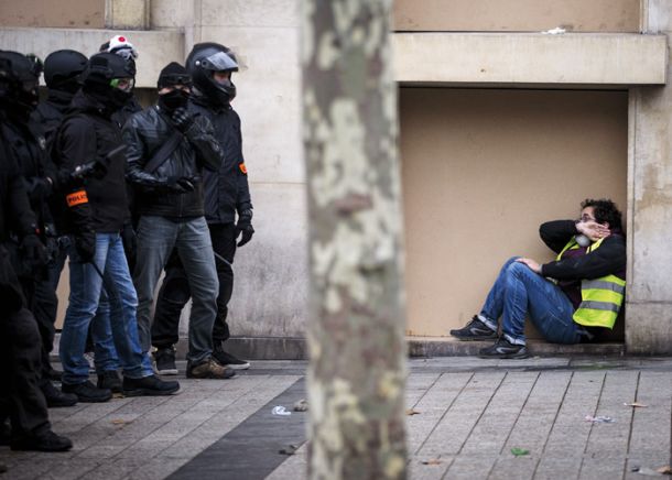 Policisti v civilu in protestnik, preplašen in stisnjen ob zid stavbe. 