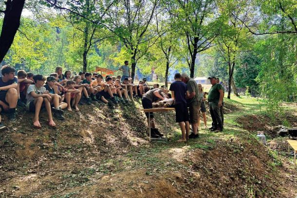 Razkosavanje divjega prašiča pred očmi otrok. Lovec Marjan Lasič je otroke pozval, naj se jim pridružijo: »Rabimo še enega junaka, da bo držal za nogo.« / Foto: Facebook, Lovska družina Fajti hrib Renče