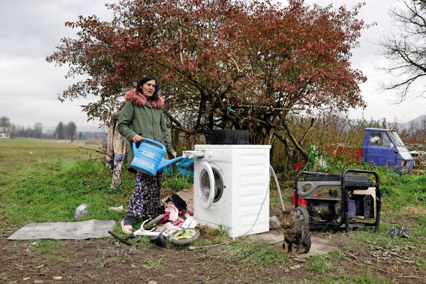 Jasna Hudorovič iz romskega naselja pri Goriči vasi pri Ribnici. Perilo perejo na prostem, v pralnem stroju, priklopljenem na dizelski agregat, in s sprotnim dolivanjem vode v stroj z vrtno zalivalko.  